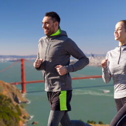 Man and woman running in front of Golden Gate Bridge