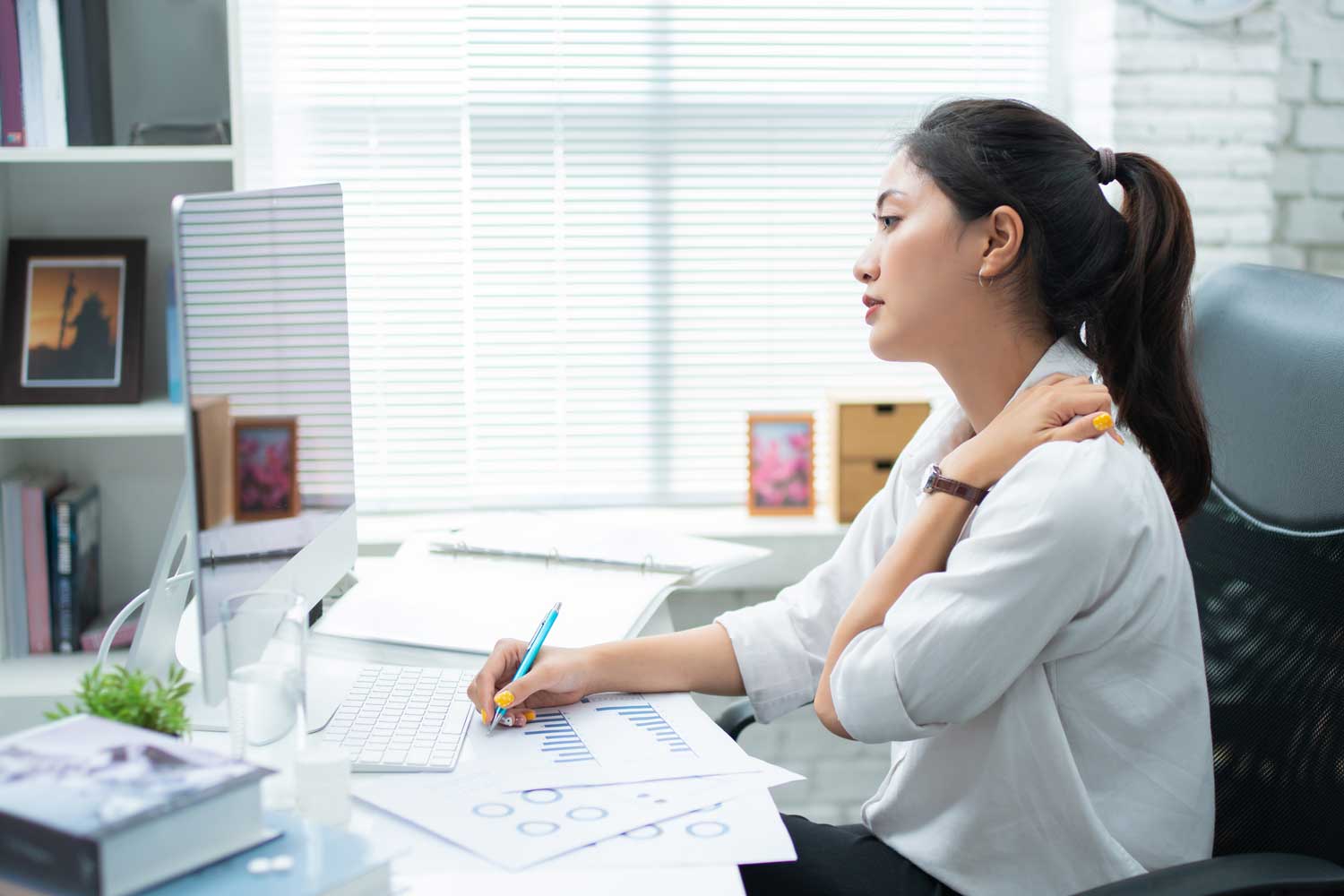 Woman in pain from sitting at work desk | Spine & Sport Physical Therapy | San Diego, Irvine, Sacramento, CA