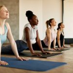 Four women doing yoga illustrates the differences in Pilates vs. yoga | Spine & Sport PT | Rancho Santa Margarita, CA Clinic
